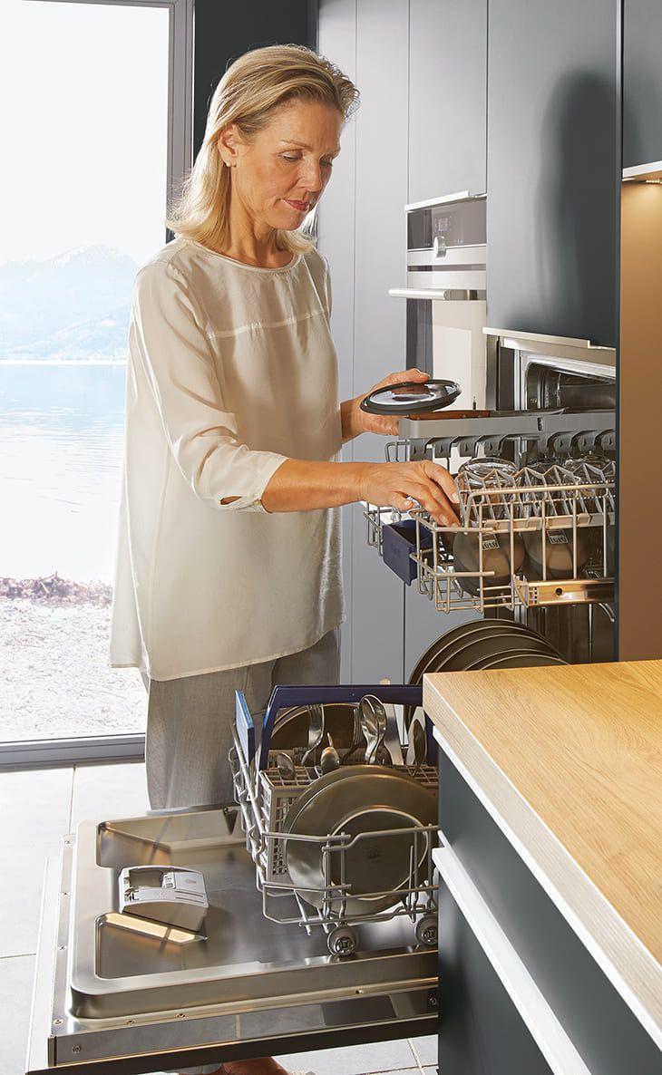 Person räumt eine Spülmaschine in Arbeitshöhe ein